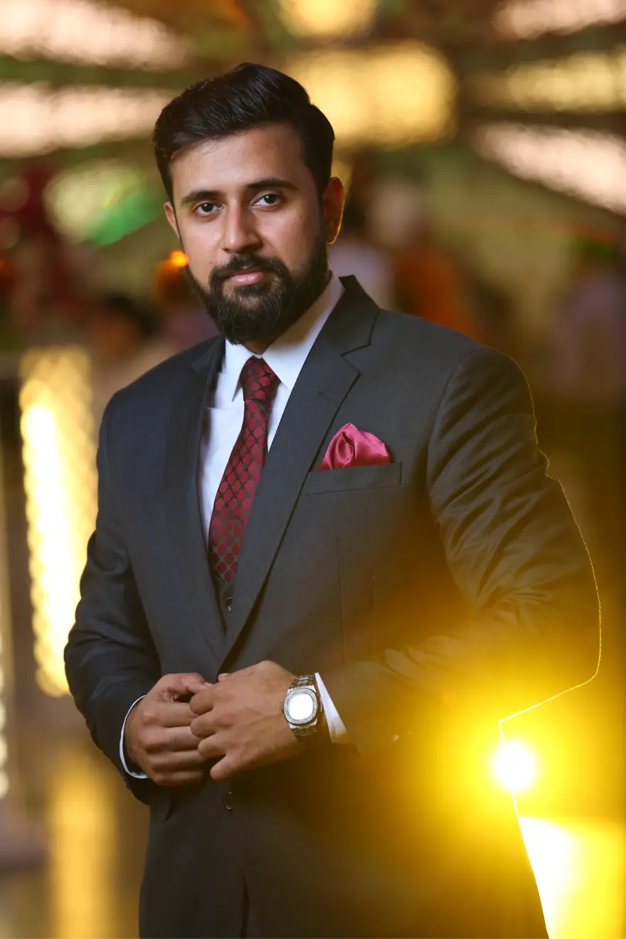 A man in a tailored suit smiles, radiating charm and professionalism.